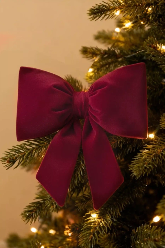 Pernă cu fundiță de Crăciun de la Needle and Thread – pernă din catifea bordo, certificată Oeko-Tex